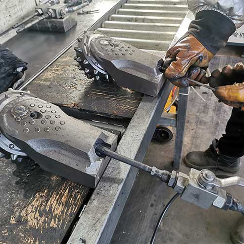 workers using special equipment making the roller bit inside vacuum then push the grease inside